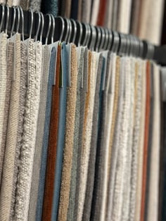 Close-up of fabric swatches in various textures and colors hanging on display rack for custom sofa upholstery options | The Furniture Mall