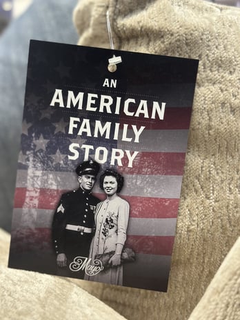Close-up of a Mayo Furniture product tag that reads “An American Family Story,” featuring a vintage photo of a military couple, symbolizing the brand’s American-made heritage and family craftsmanship. | The Furniture Mall