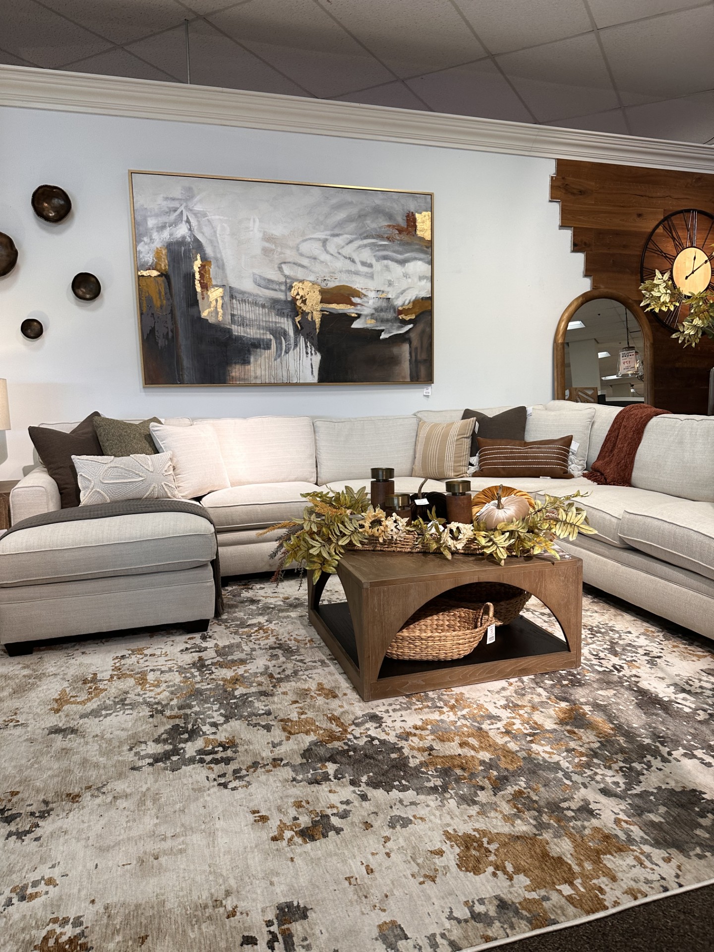 Fall living room display at Furniture Mall in Topeka featuring rust accents, neutral pumpkins, fall leaves and cozy textures.